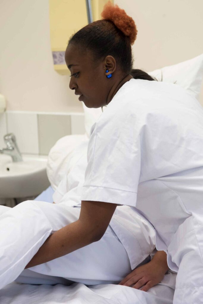 Élève en tenue de soin auprès d'une patiente sur le plateau technique sanitaire