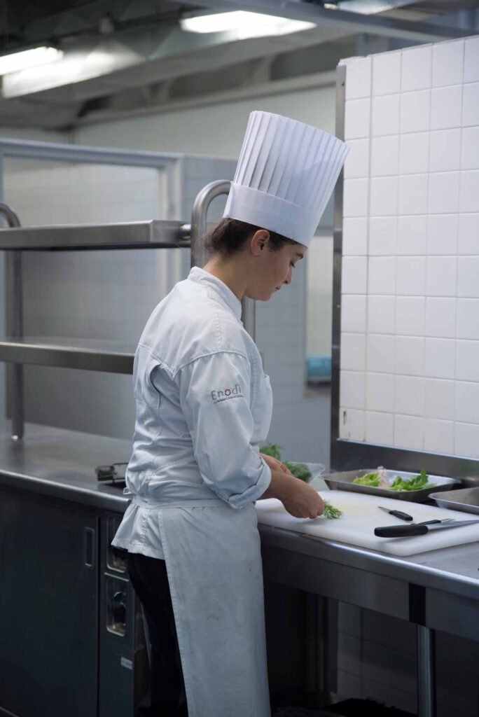 Élève cuisinier en toque au plan de travail de la cuisine pédagogique